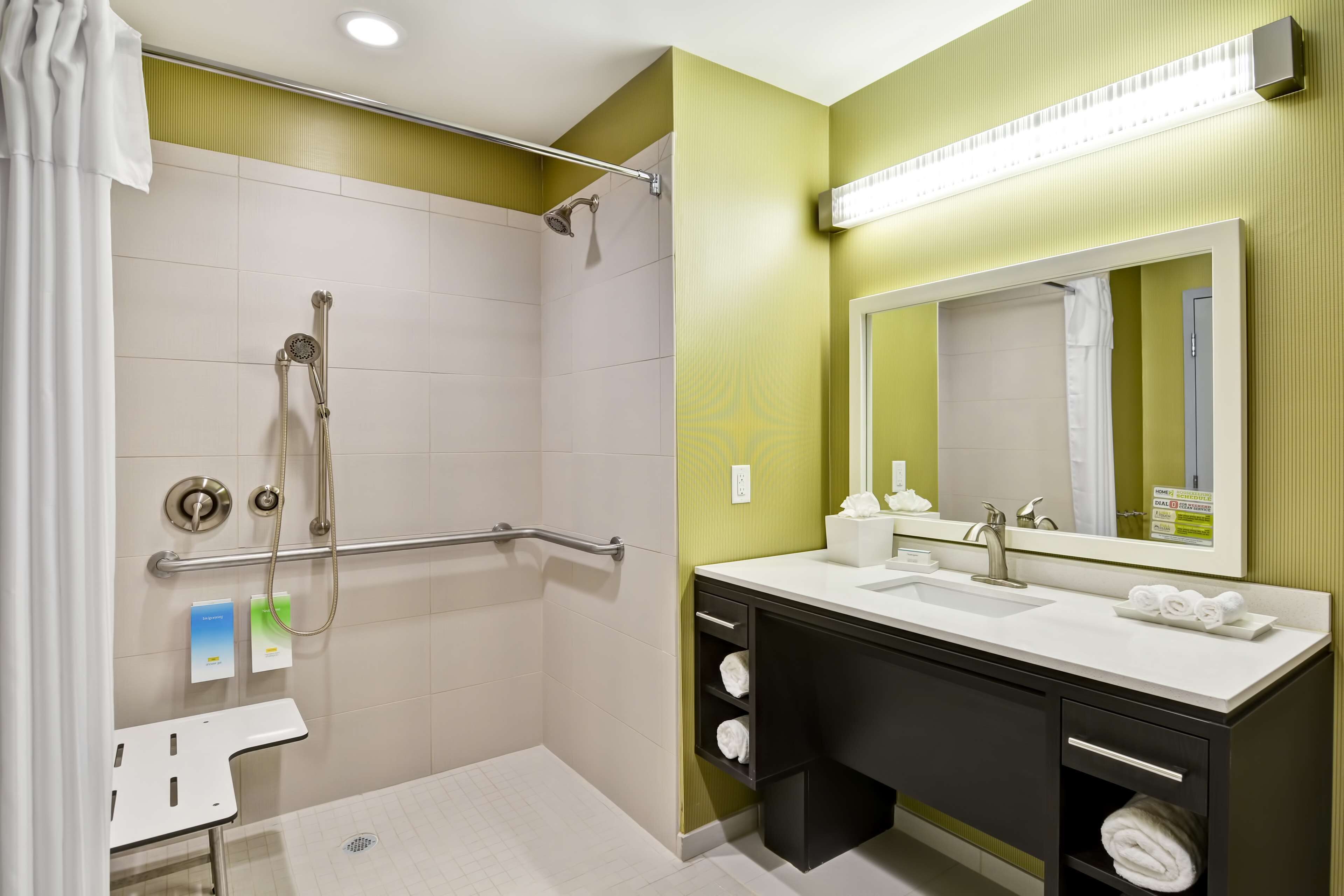 A bathroom with a shower, a sink, a mirror, and a towel rack.