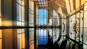 A modern interior with large windows, a high ceiling, and a view of the water outside.