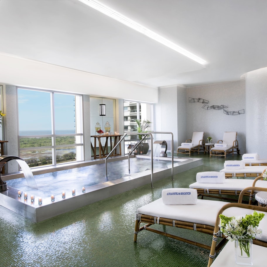 A spa area with a hot tub, lounge chairs, and a view of the ocean.