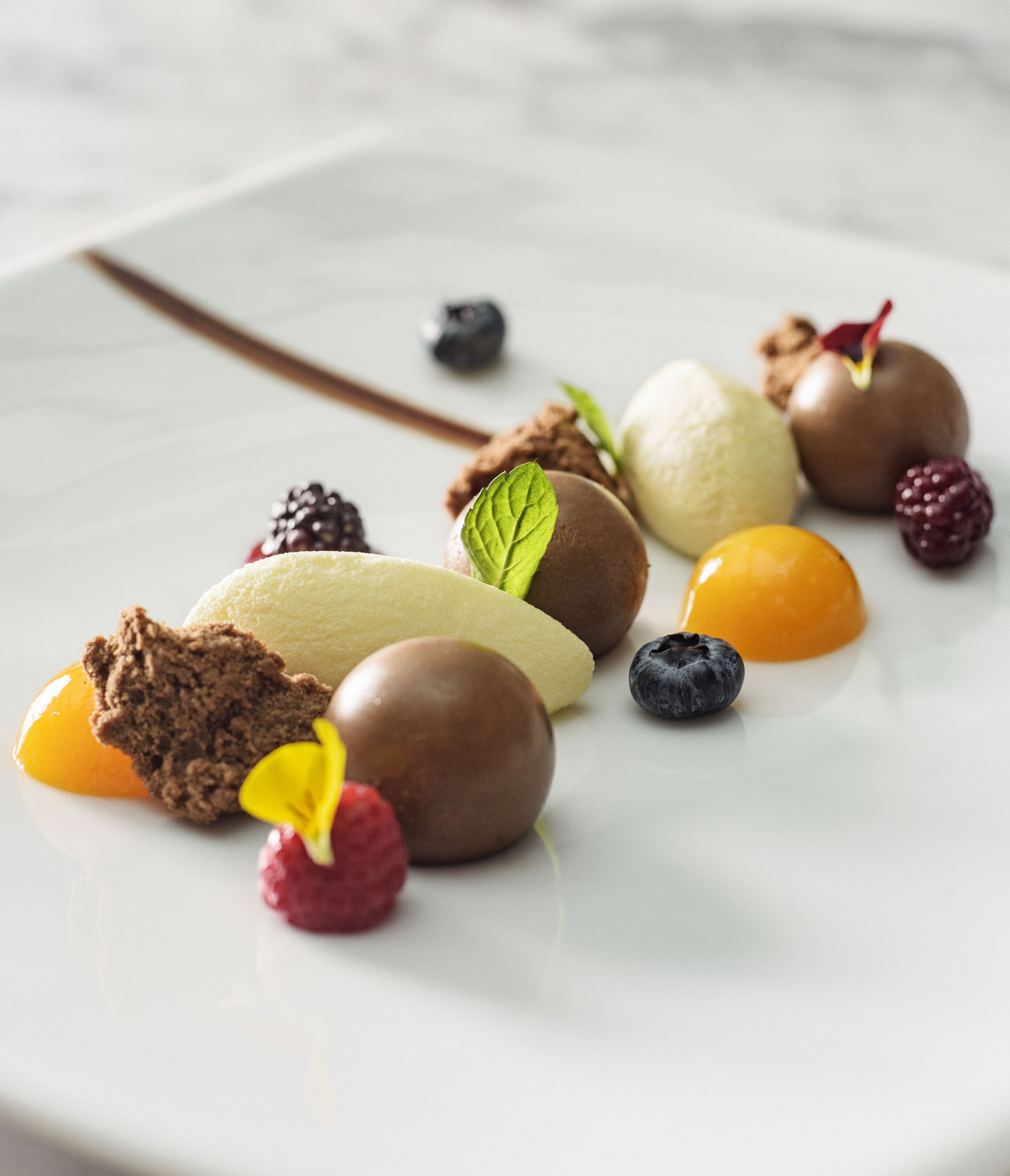 Un plato de postre con diferentes frutas y trozos de chocolate.