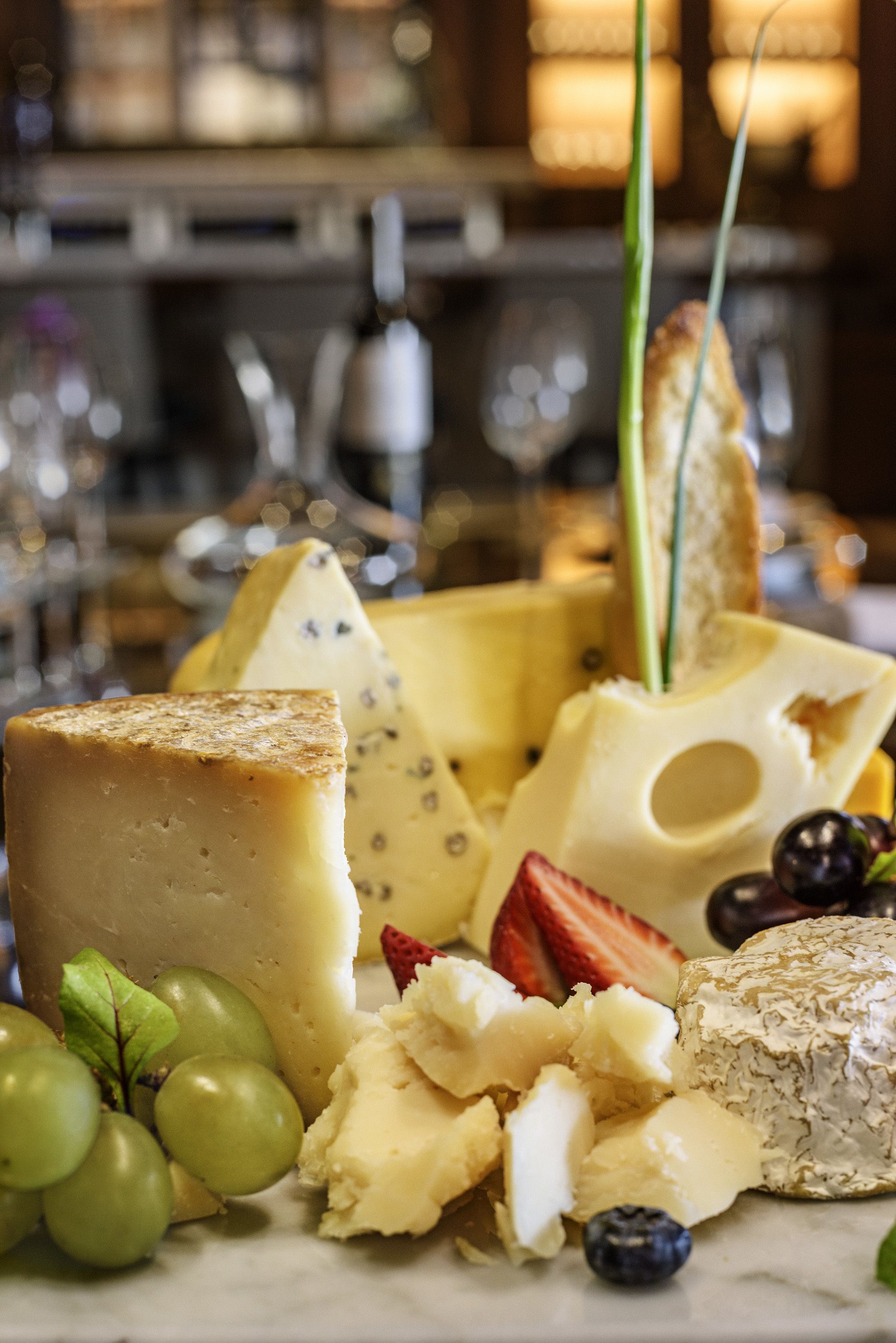 A variety of cheeses and fruits on a marble surface.
