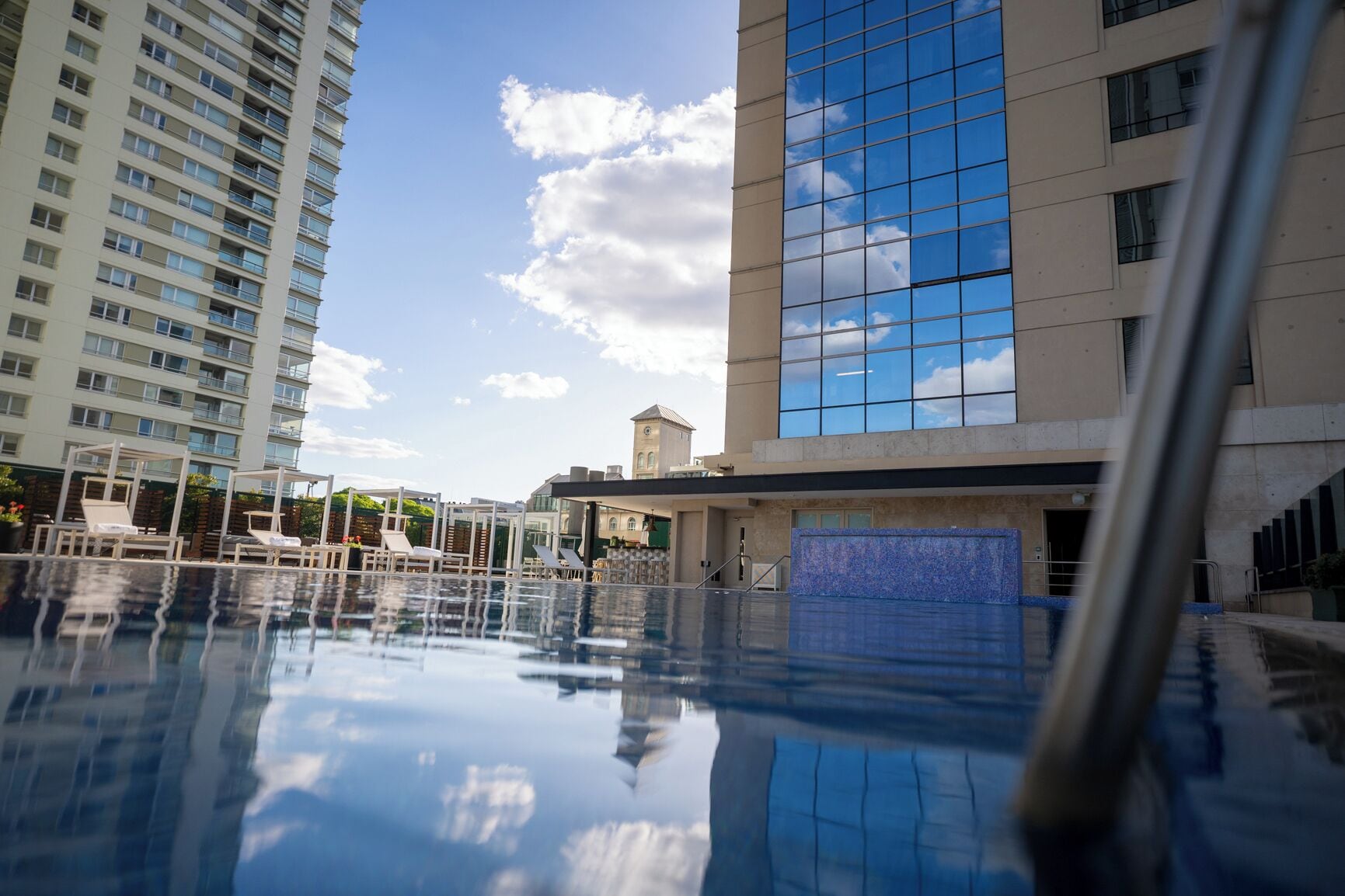 A swimming pool with lounge chairs and a view of high-rise buildings.