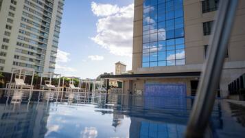 A swimming pool with lounge chairs and a view of high-rise buildings.