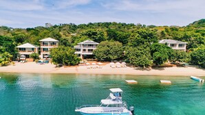 Una propiedad costera con varias edificaciones, una playa y un bote en el agua.
