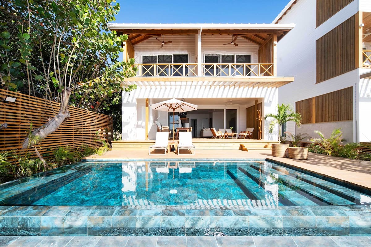 Ein modernes, zweistöckiges Gebäude mit Swimmingpool, Außenbereich und einer Holzterrasse.
