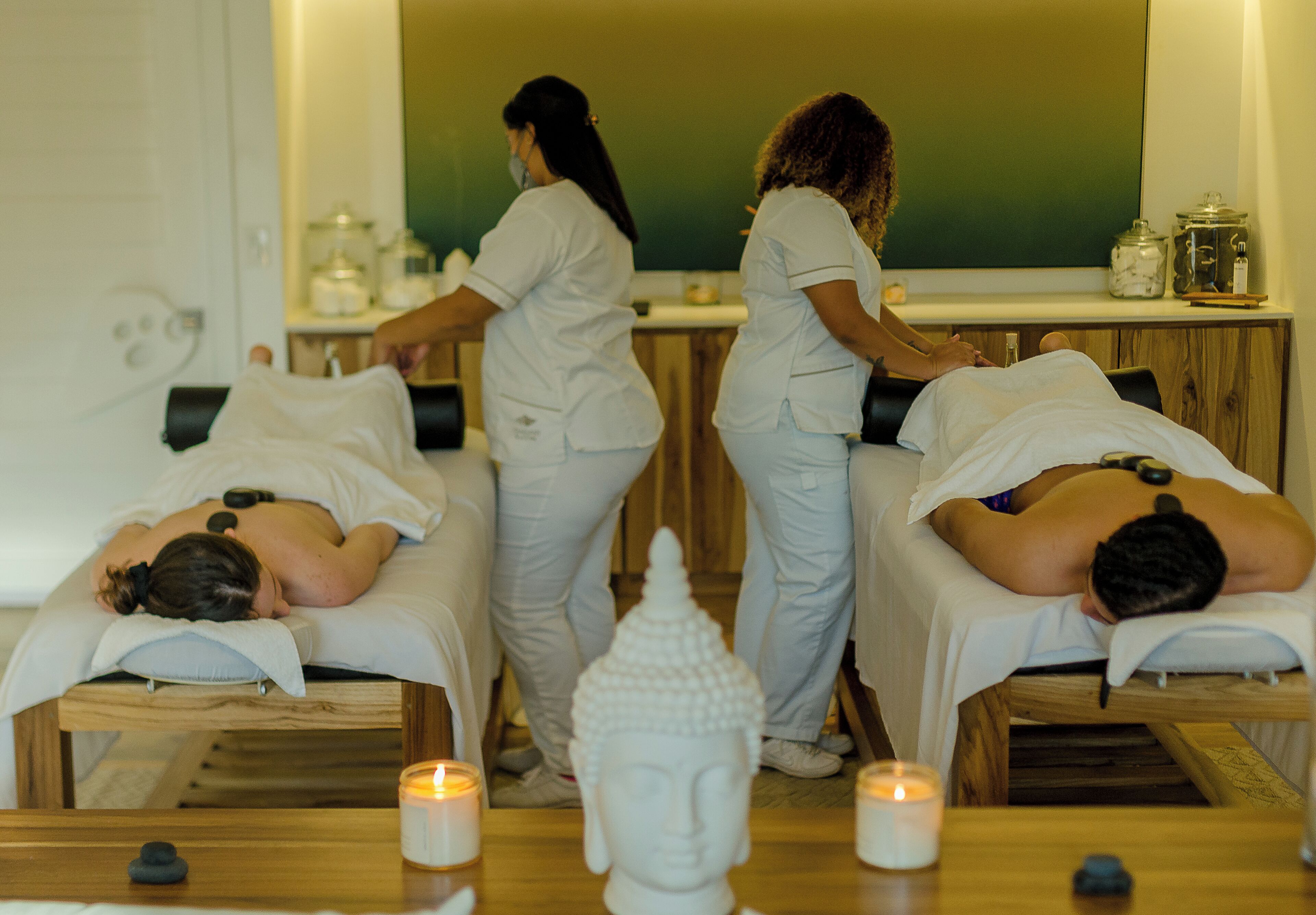 Ein Spa-Raum mit zwei Massageliegen, einer grünen Kreidetafel und Kerzen.
