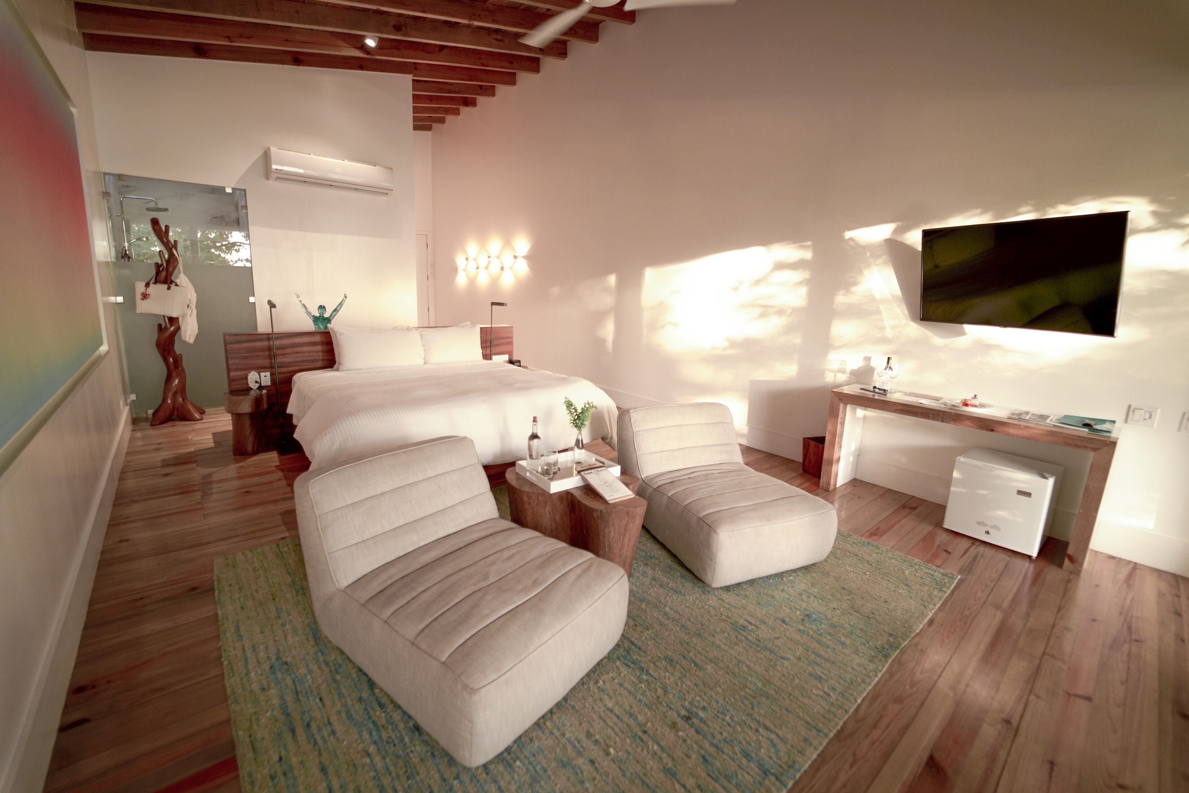 Un dormitorio moderno con una cama grande, dos sofás, un escritorio y un televisor.