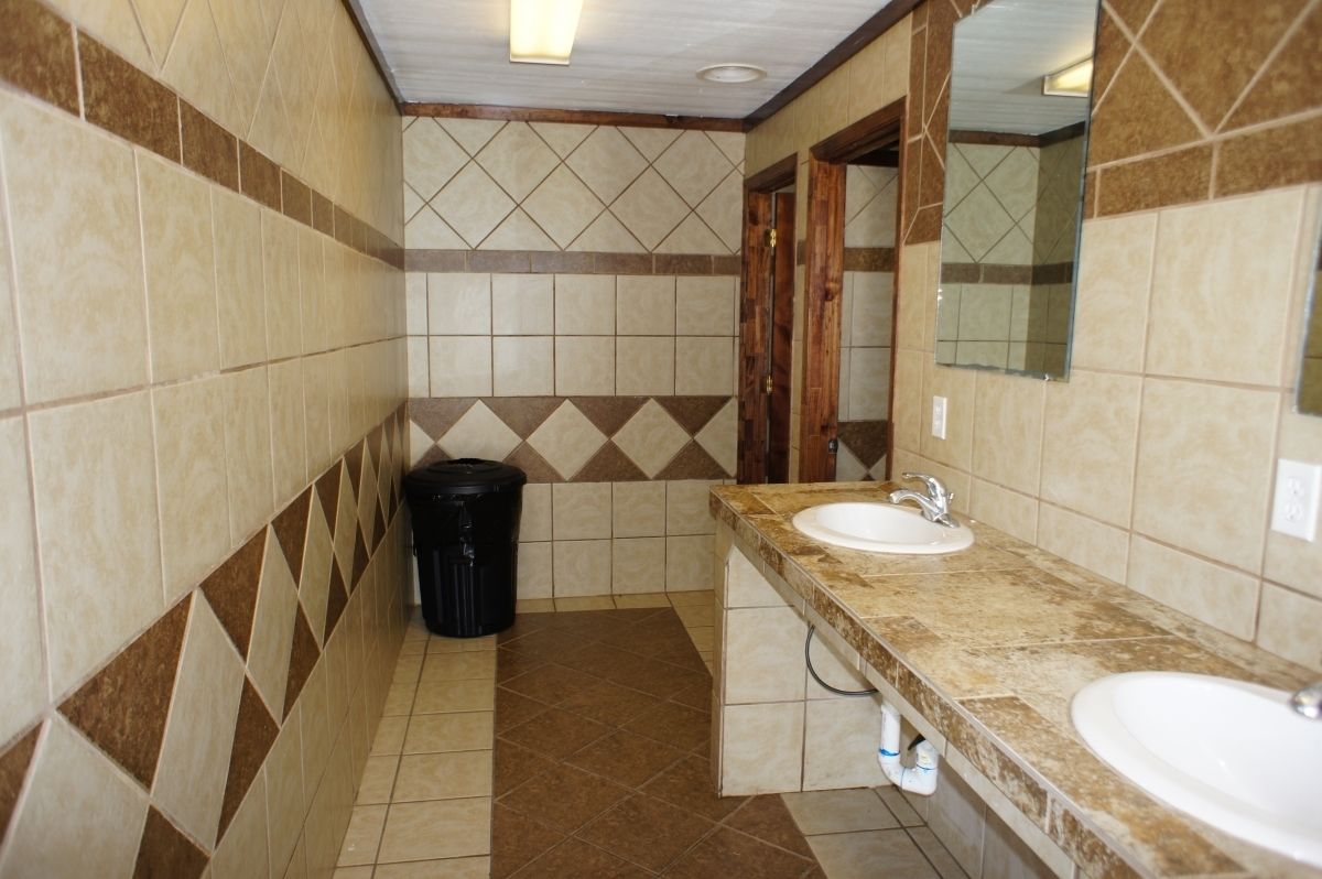A bathroom with two sinks, a mirror, and a trash bin.