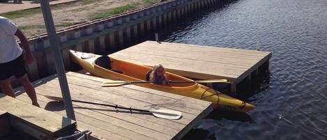 A wooden dock with a yellow kayak and a paddle.