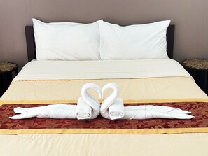A neatly made bed with white pillows and a decorative towel arrangement.
