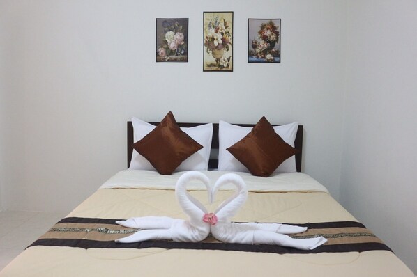 A hotel room with a bed, two pillows, and three framed floral paintings on the wall.