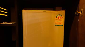 A white refrigerator with a sticker on it, placed in a dimly lit room.