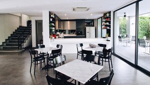A modern kitchen with a central island, black chairs, and a dining area with tables and chairs. - The Sala Pattaya (Pattaya)