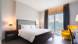 A hotel room with a large bed, a desk, a chair, and a window with curtains. - The Sala Pattaya (Pattaya)