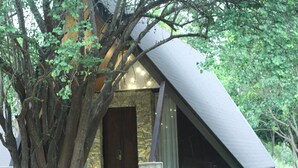 A treehouse with a stone exterior and a sloped roof, surrounded by lush greenery. - Liyya Water Villas (Dambulla)
