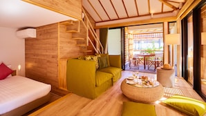 Une chambre d’hôtel moderne avec un plafond en bois, un canapé, un lit, une table à manger agrémentée d’un panier de collations et un escalier.