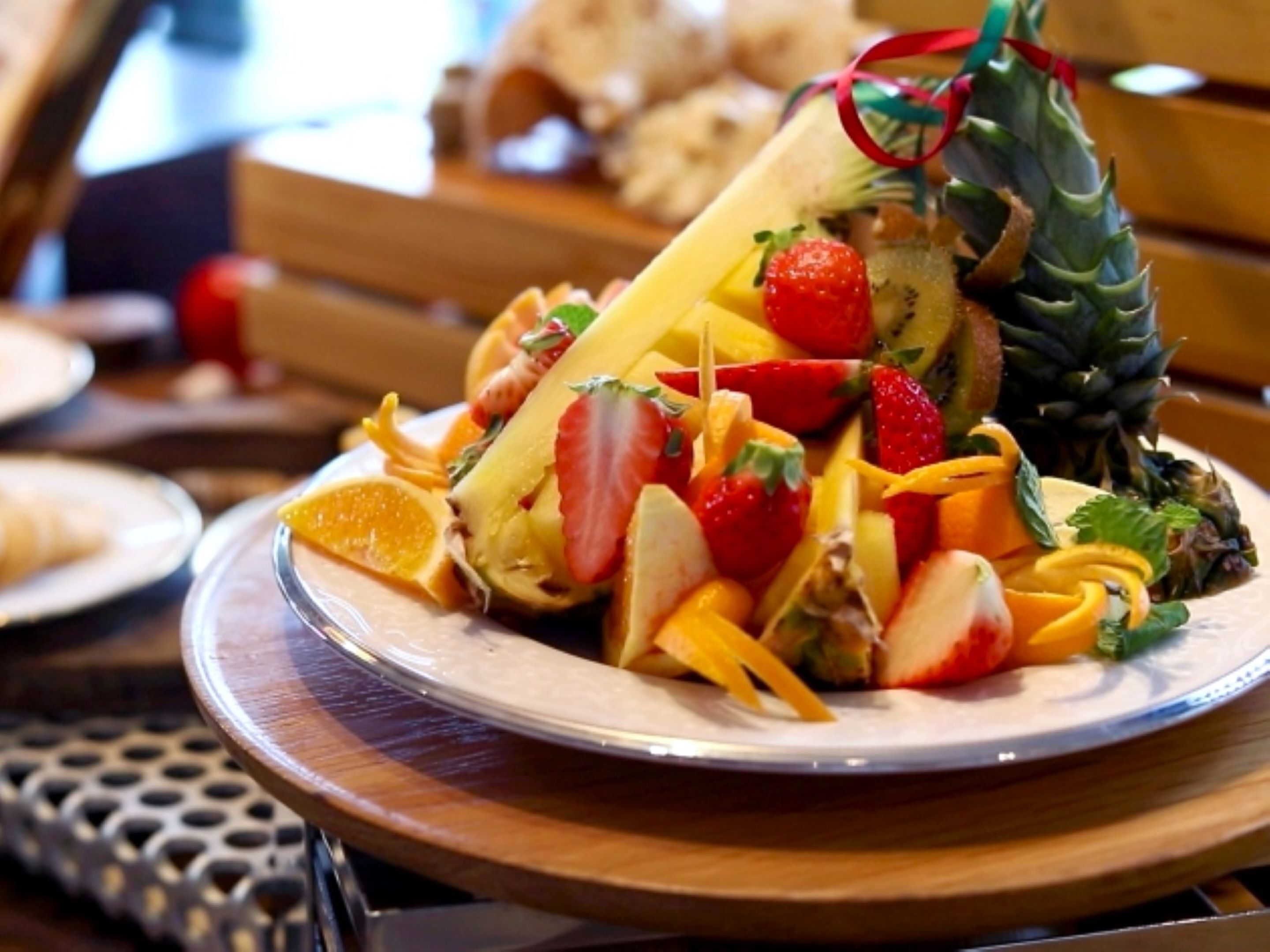 Un plato de ensalada de frutas con fresas, piña y gajos de naranja.