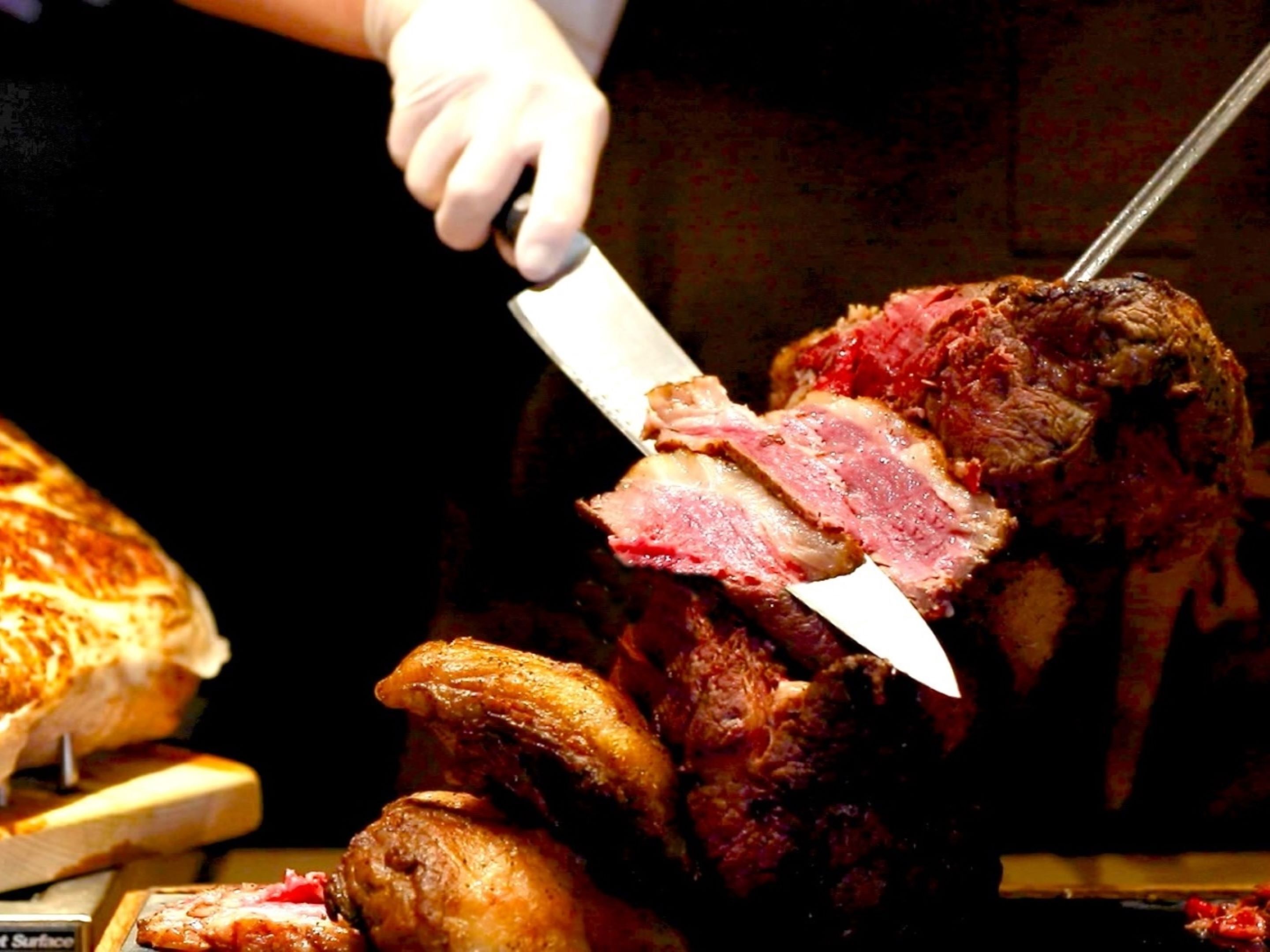Una persona cortando un trozo grande de carne con un cuchillo.