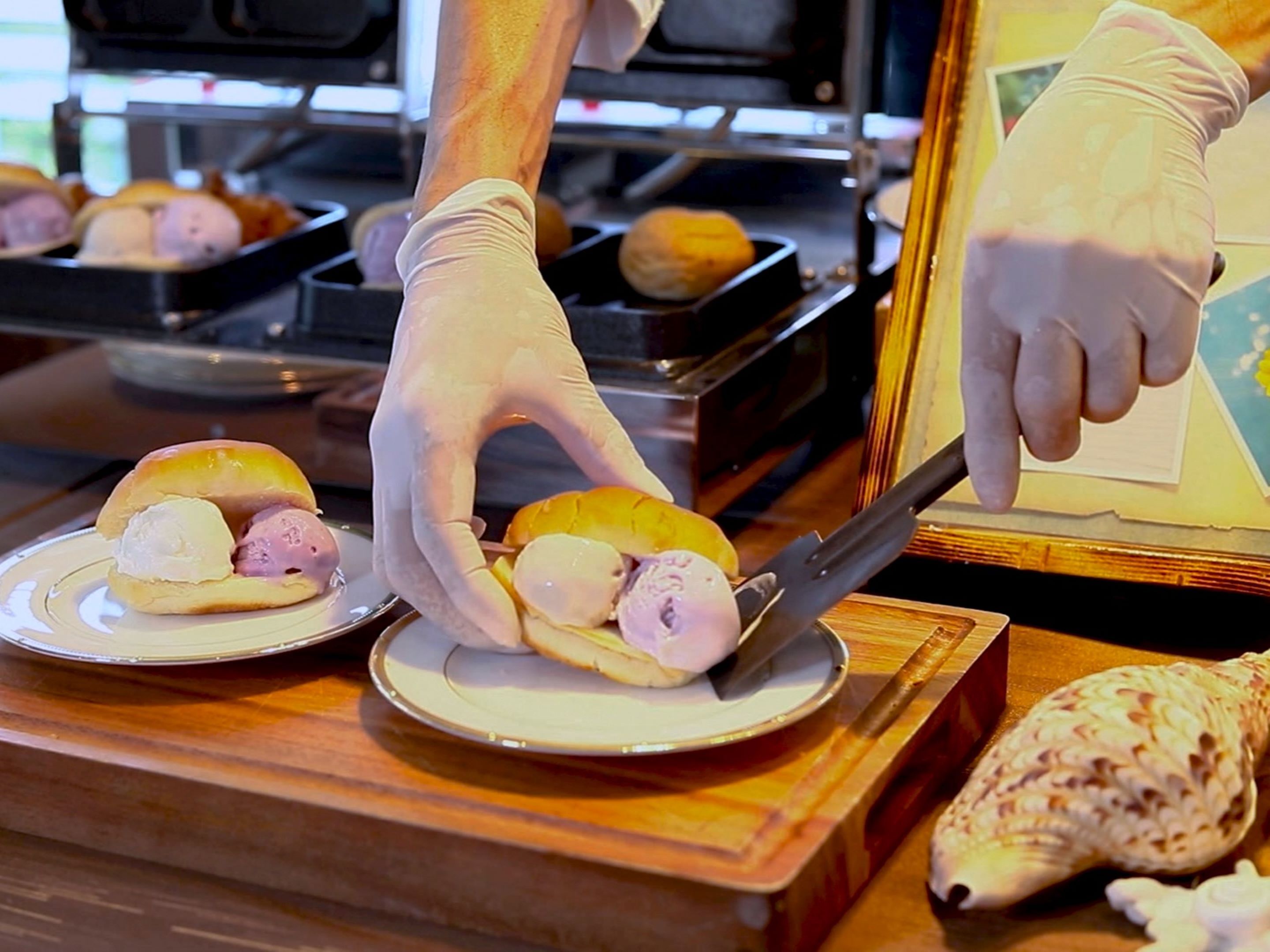 A person preparing food, wearing gloves, and using a spatula on a plate.