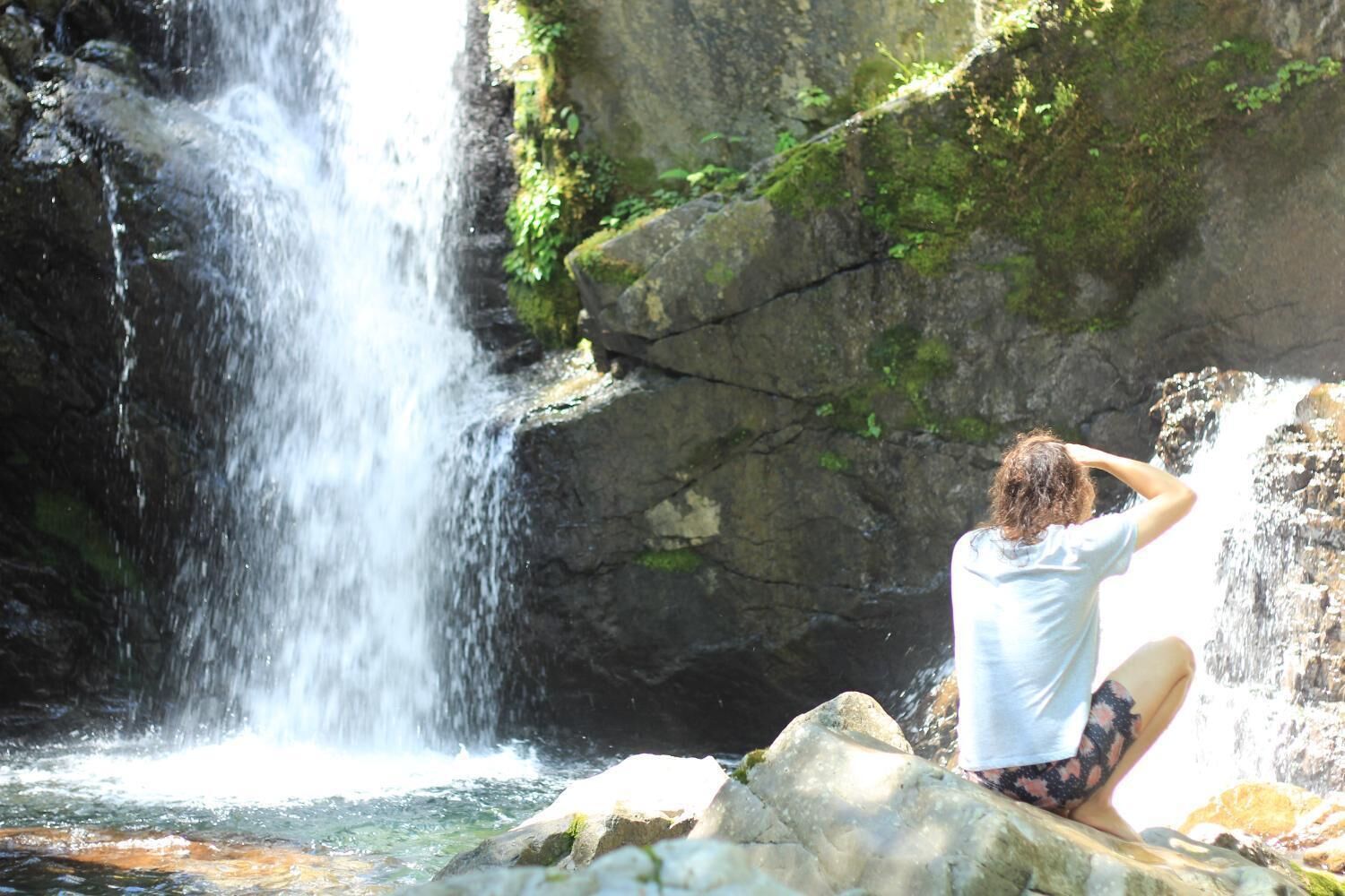 A person sitting on rocks by a waterfall.