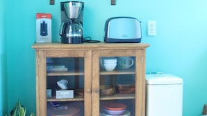 Una cocina con un armario de madera, una cafetera y un tostador sobre la encimera.