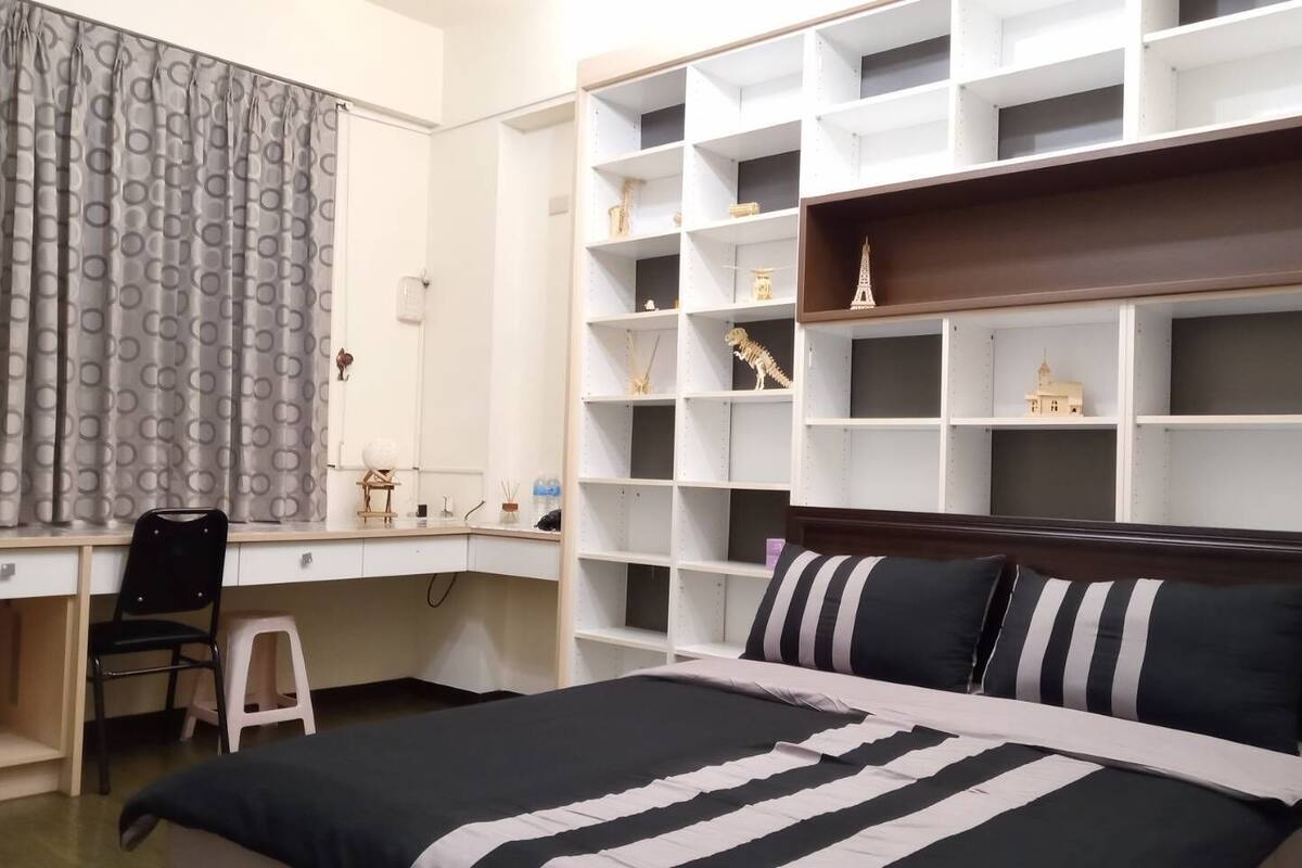 A bedroom with a bed, a desk, and built-in shelving.