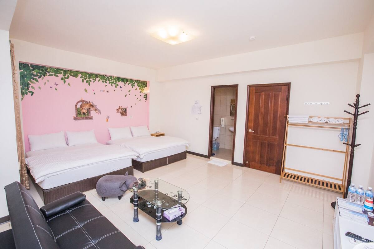A hotel room with a bed, a sofa, a glass coffee table, and a wardrobe.