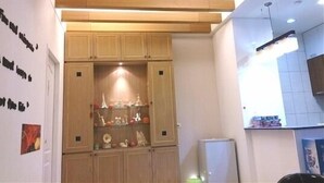 Una cucina con mobili in legno, una mensola a incasso con oggetti decorativi e un frigorifero.