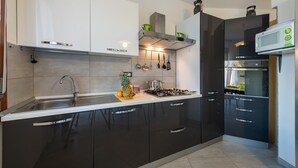 Eine moderne Küche mit dunklen Schränken, einer Edelstahlspüle und einem eingebauten Backofen.