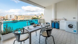 Ein Balkon mit Tisch und Stühlen, einer Waschmaschine und blauen Gasflaschen.