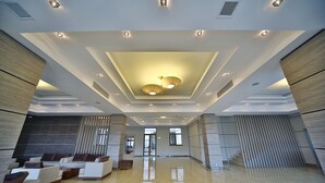 Un hall d’entrée spacieux avec un plafond haut, des luminaires encastrés et un grand lustre central.