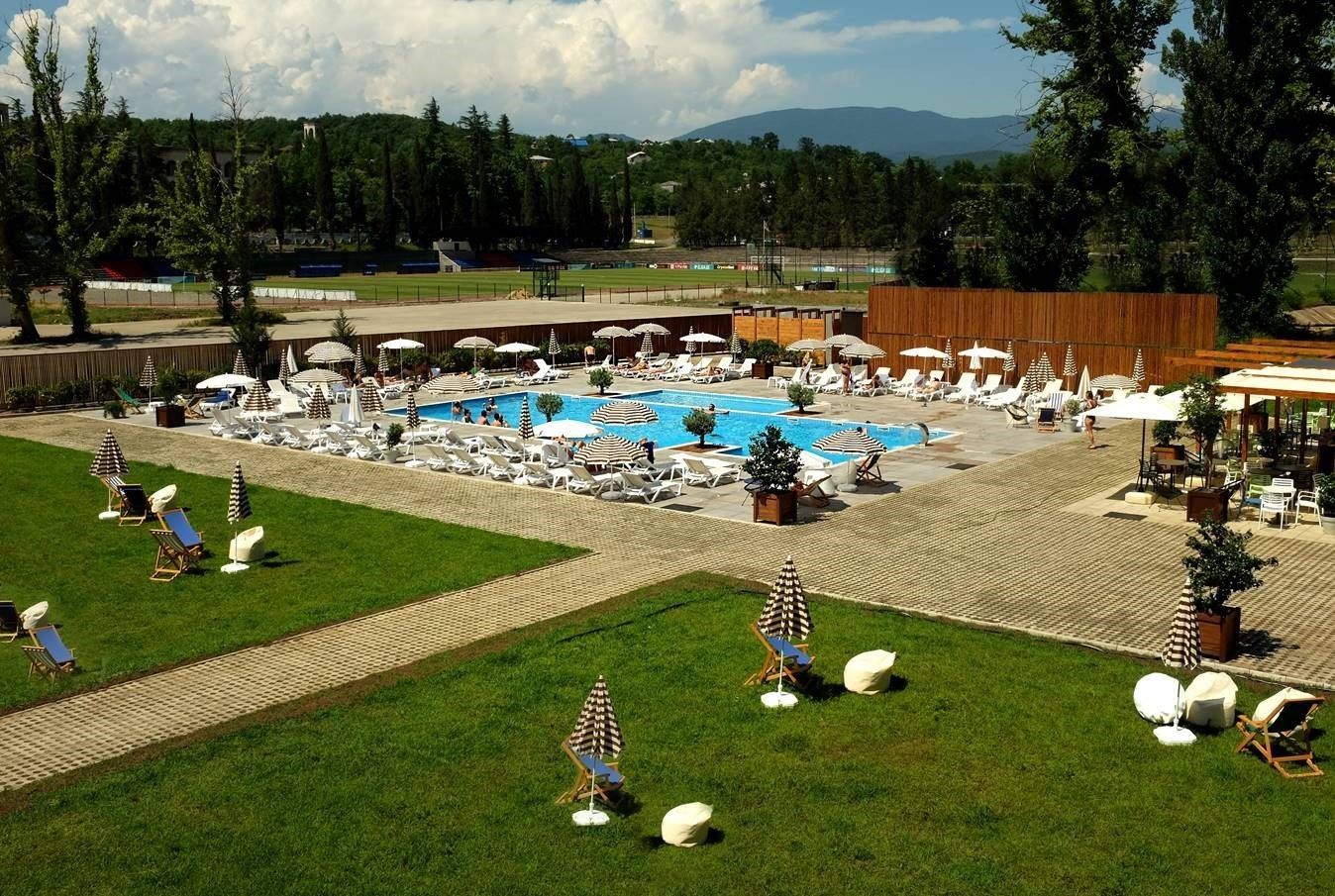Un resort con una piscina grande, sillones de sol, sombrillas y vistas a las montañas.