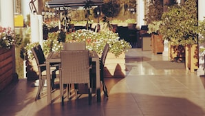 Une terrasse extérieure avec des meubles en osier, un parasol à rayures et des plantes en pot.