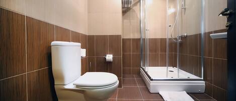 Un baño moderno con inodoro, ducha y cabina de ducha con paredes de vidrio.