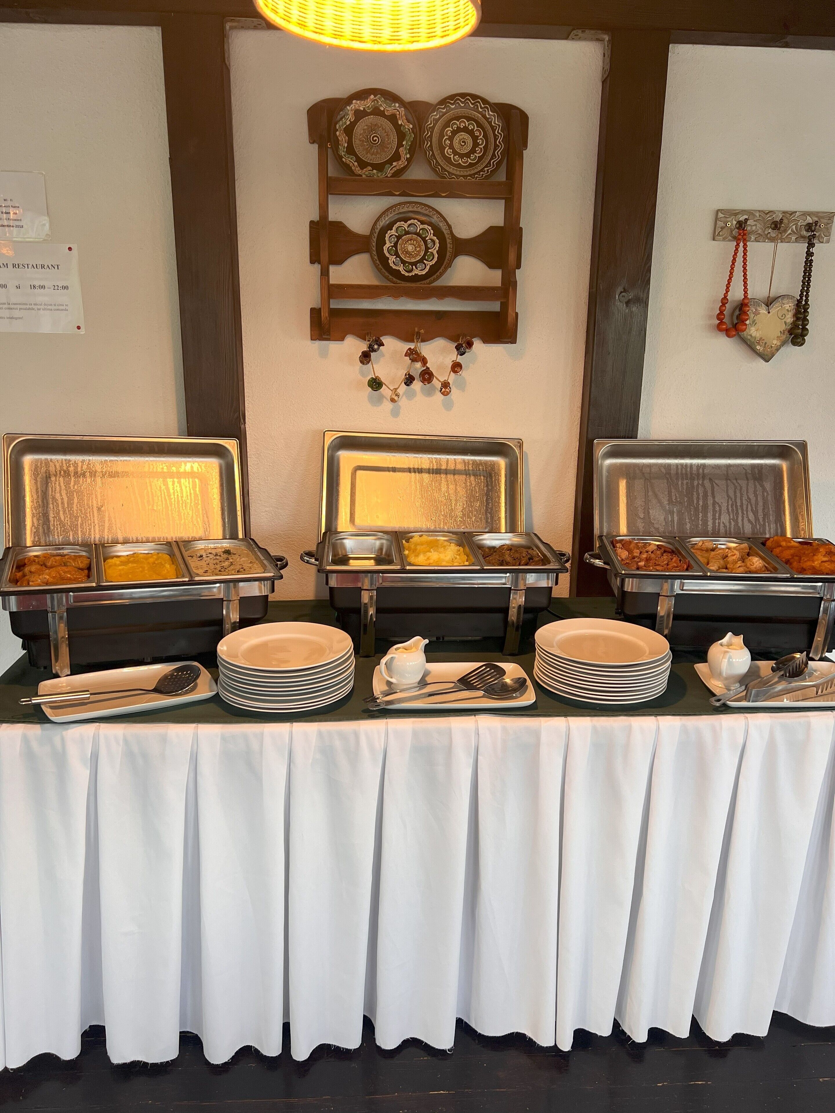 A buffet setup with multiple serving trays, plates, and utensils.
