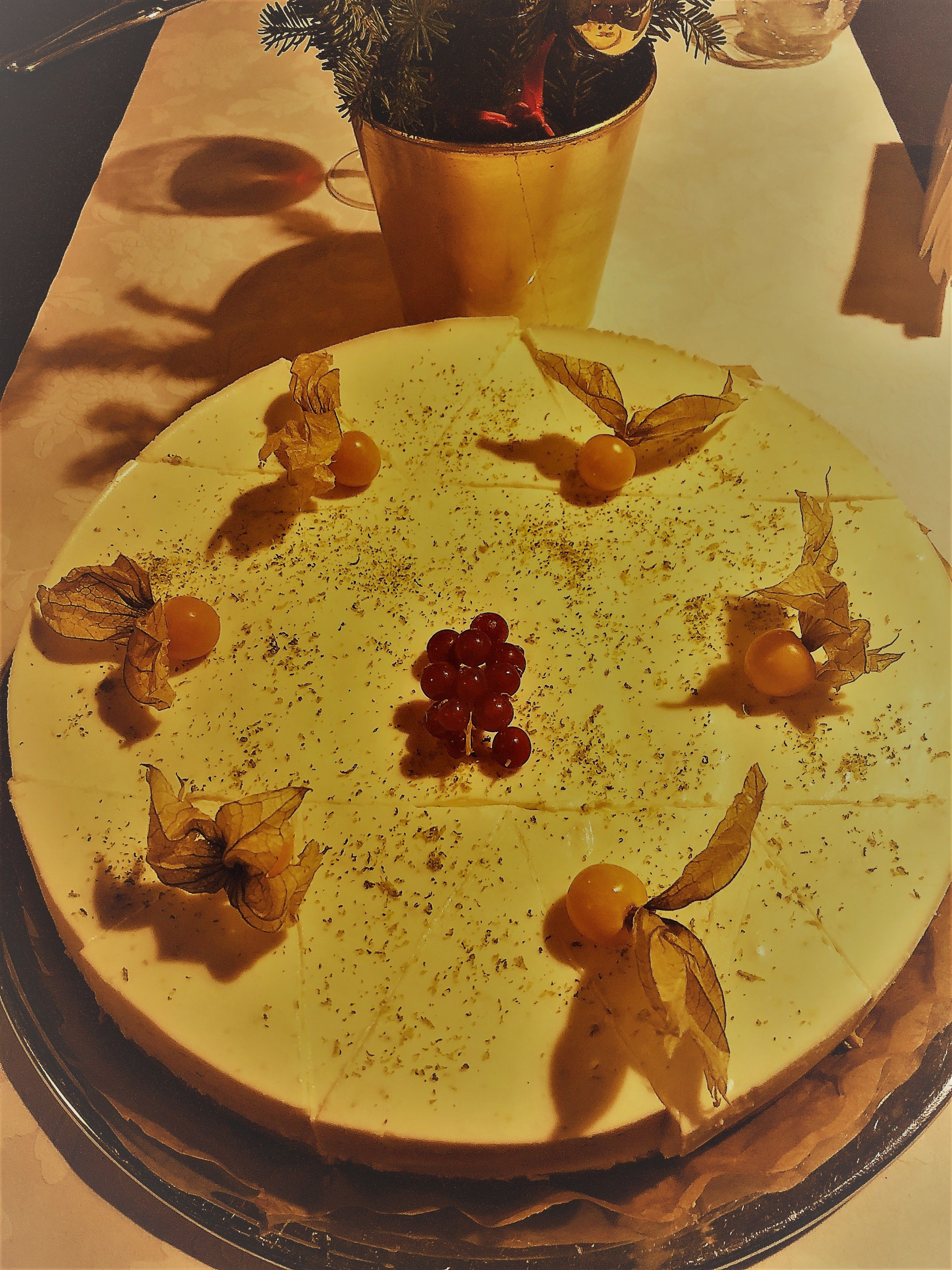 En rund dessert med tørrede blade og bær på en tallerken.
