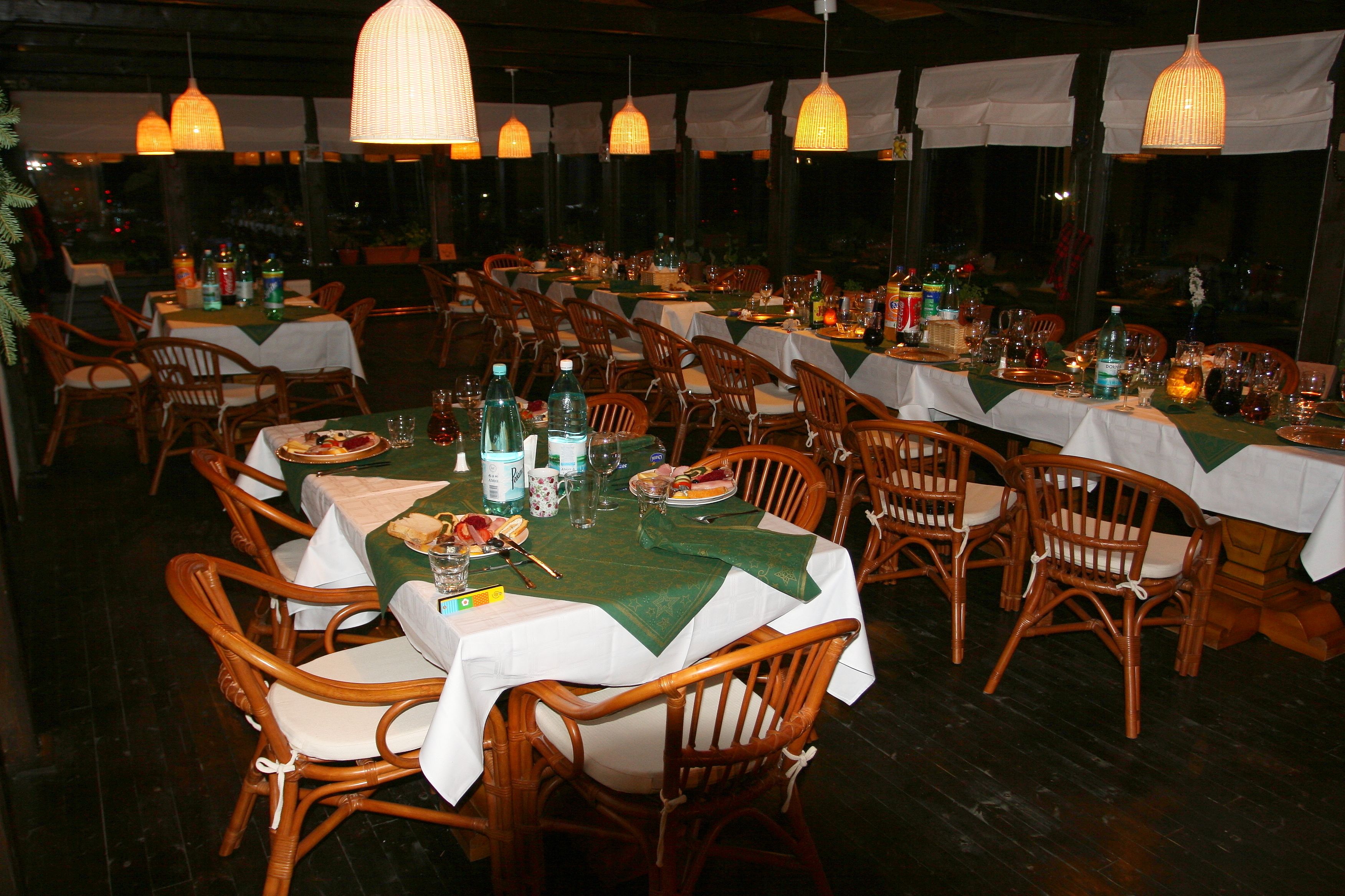 A restaurant with multiple tables set for dining, each with chairs and tablecloths.