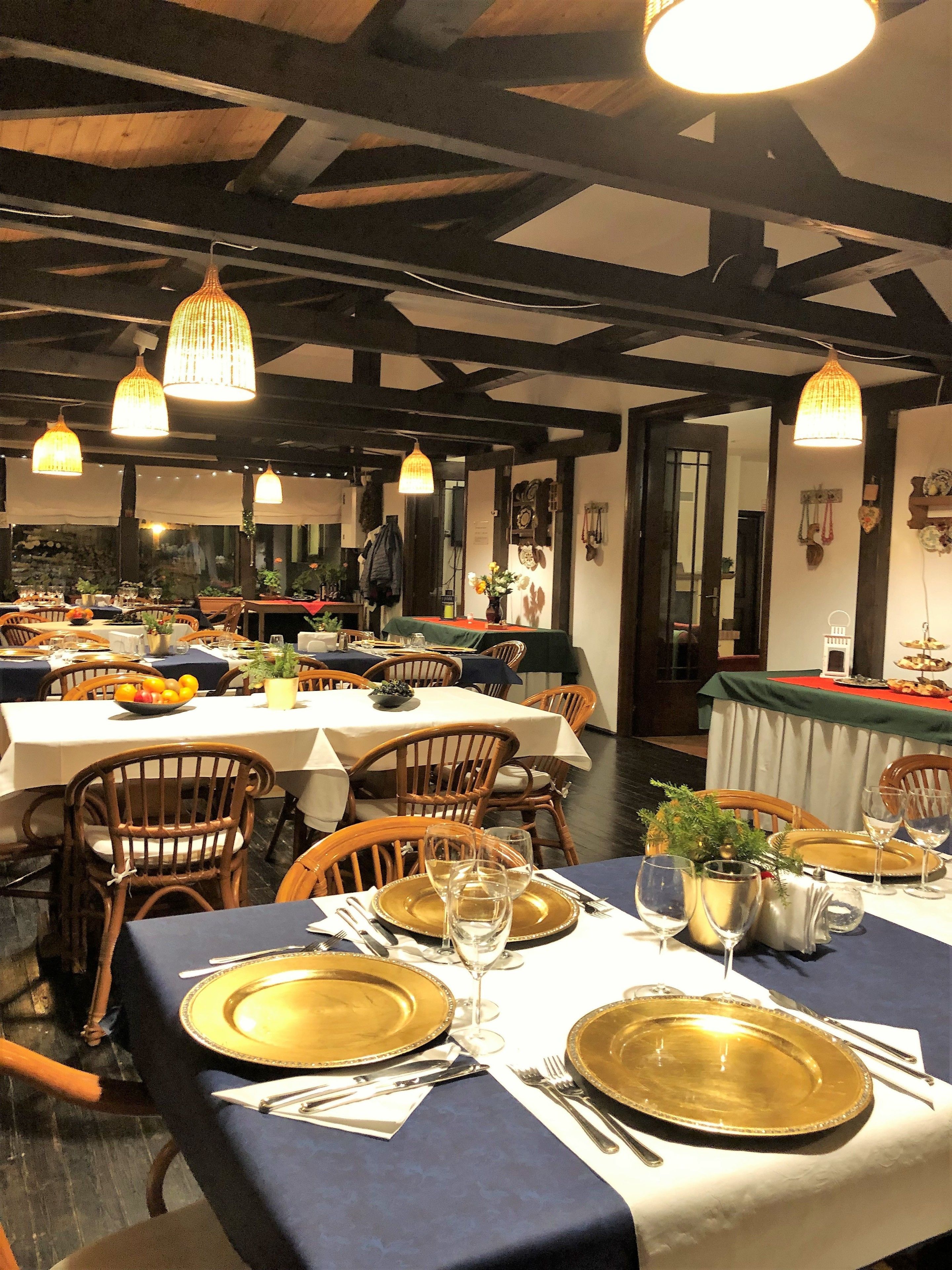 Un restaurante con varias mesas dispuestas para comer, con sillas de madera y platos con detalles dorados.