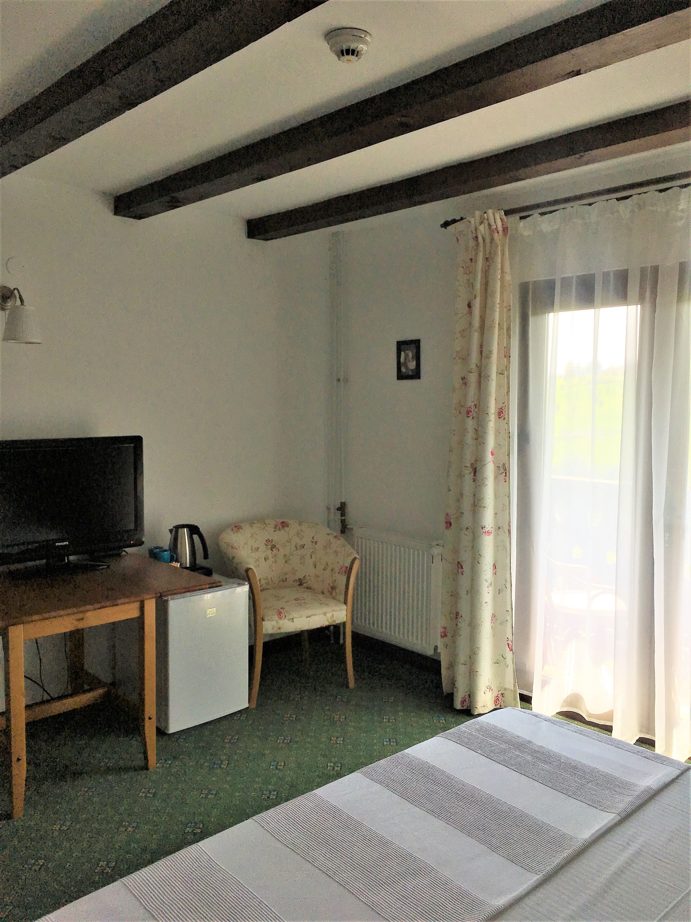 A room with a bed, a desk with a television, a chair, and a radiator.