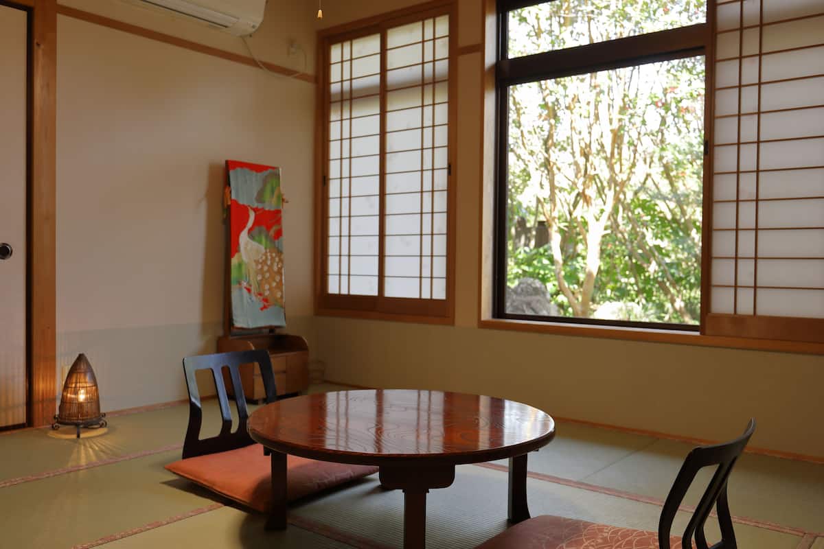 A traditional Japanese room with tatami flooring, a round wooden table, and shoji screens.