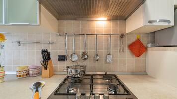 Cozinha com fogão a gás, utensílios pendurados e painel de azulejos.