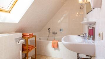 Ein modernes Badezimmer mit Dachfenster, einer Badewanne, einem Waschbecken und einer Holzablage mit Handtüchern.