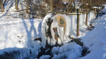 Zona exterior cubierta de nieve con una valla de madera y una abertura circular.
