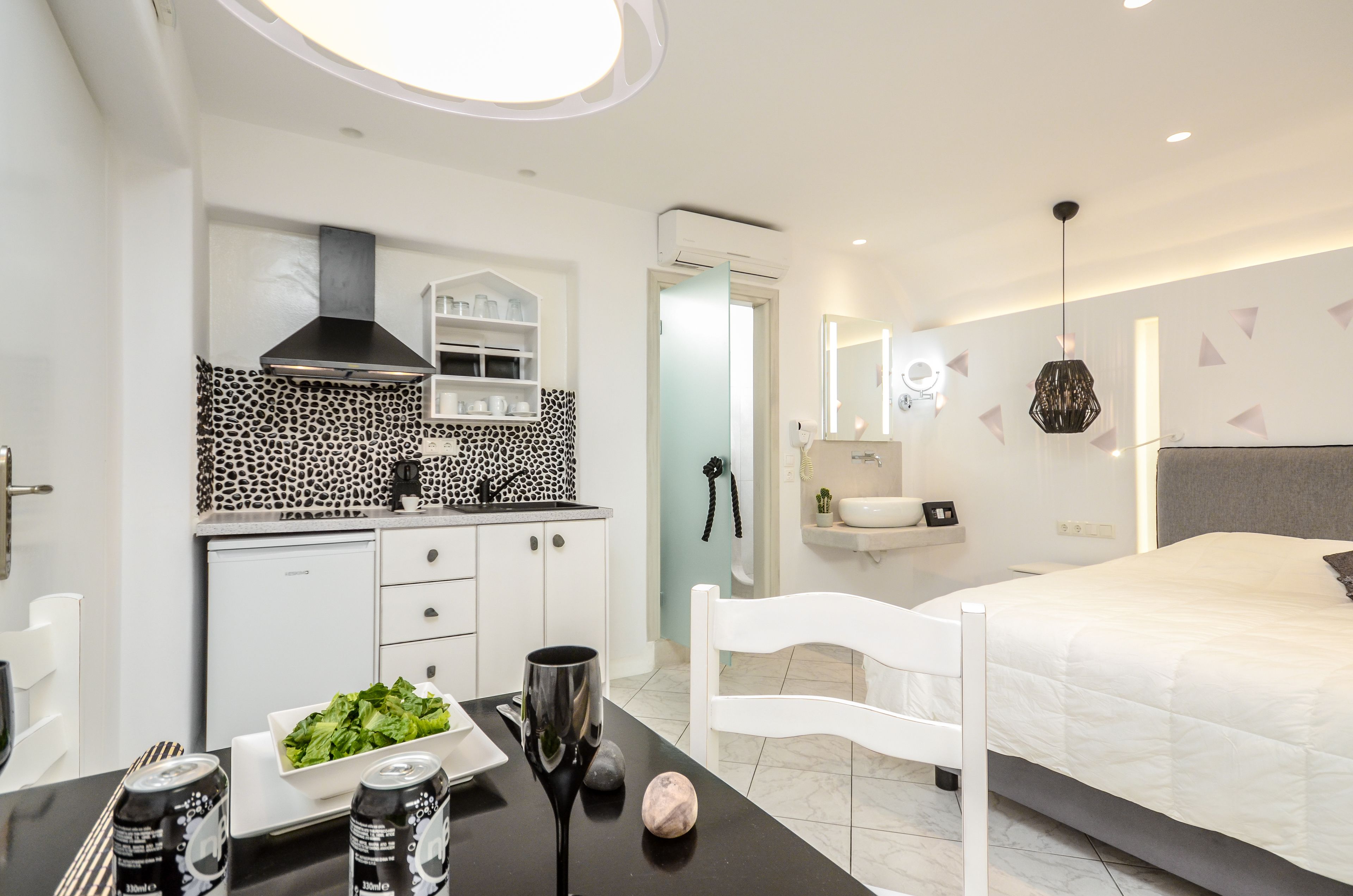 Una habitación de hotel moderna con cama, kitchenette pequeña y baño.