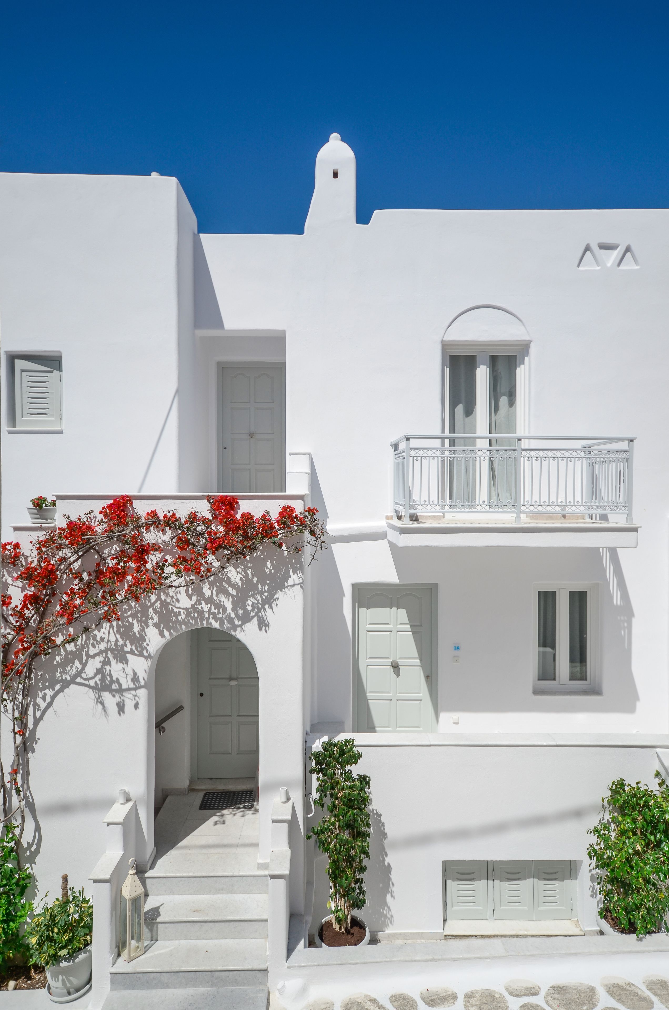 A white building with a balcony, a door, and a small window.