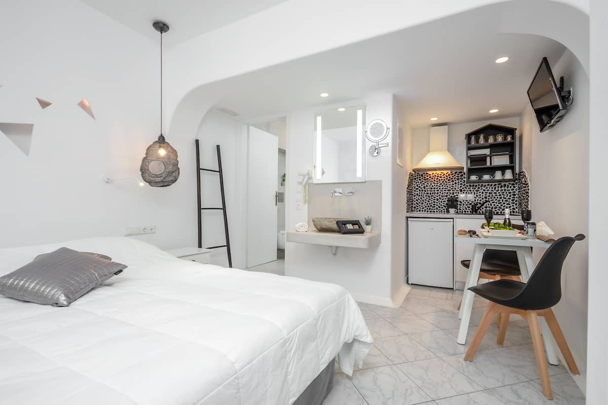 Ein modernes Hotelzimmer mit einem Bett, einem Schreibtisch und einer Küchenzeile.