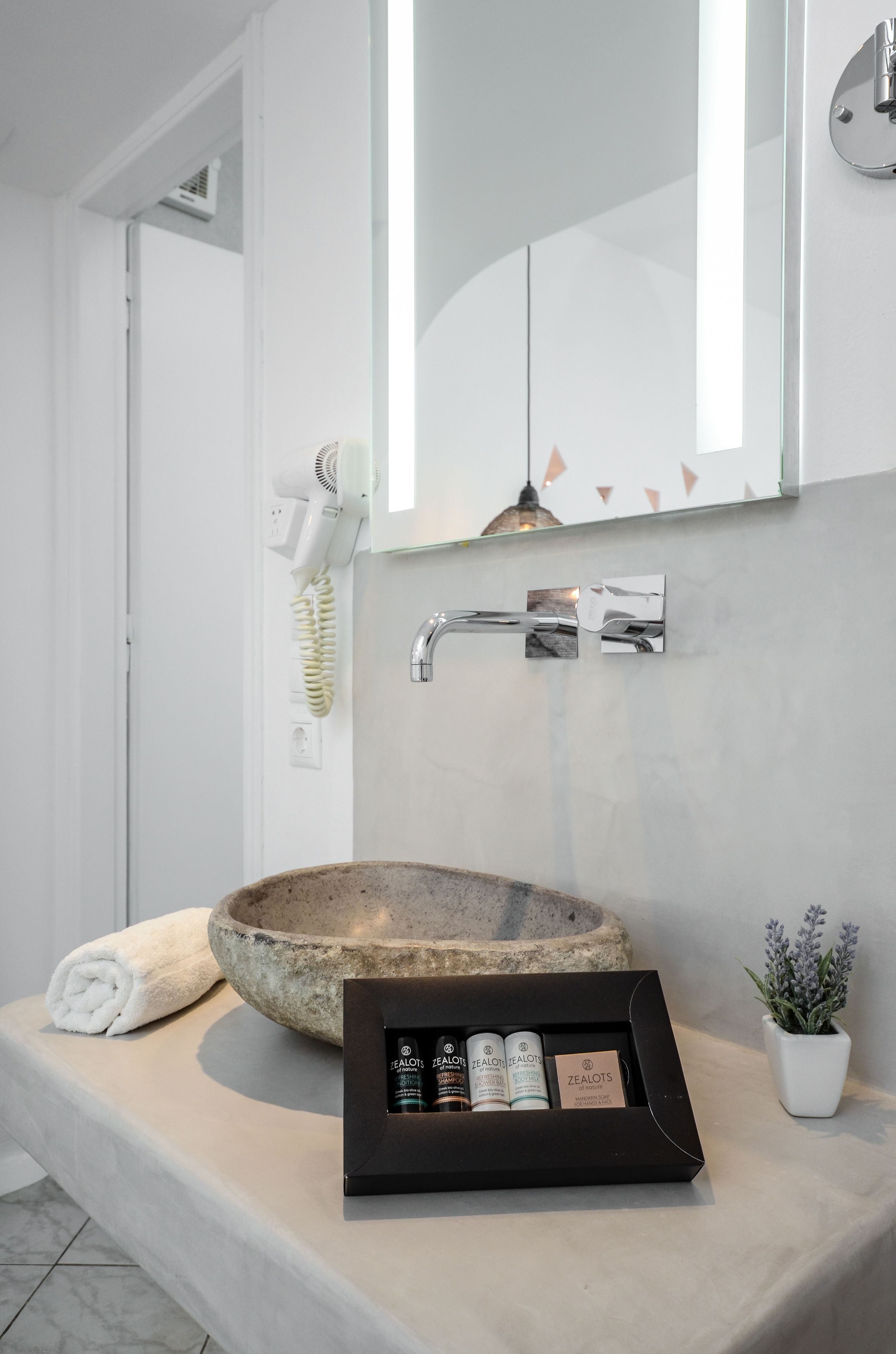 A bathroom with a stone sink, a towel, a hairdryer, and a framed product display.