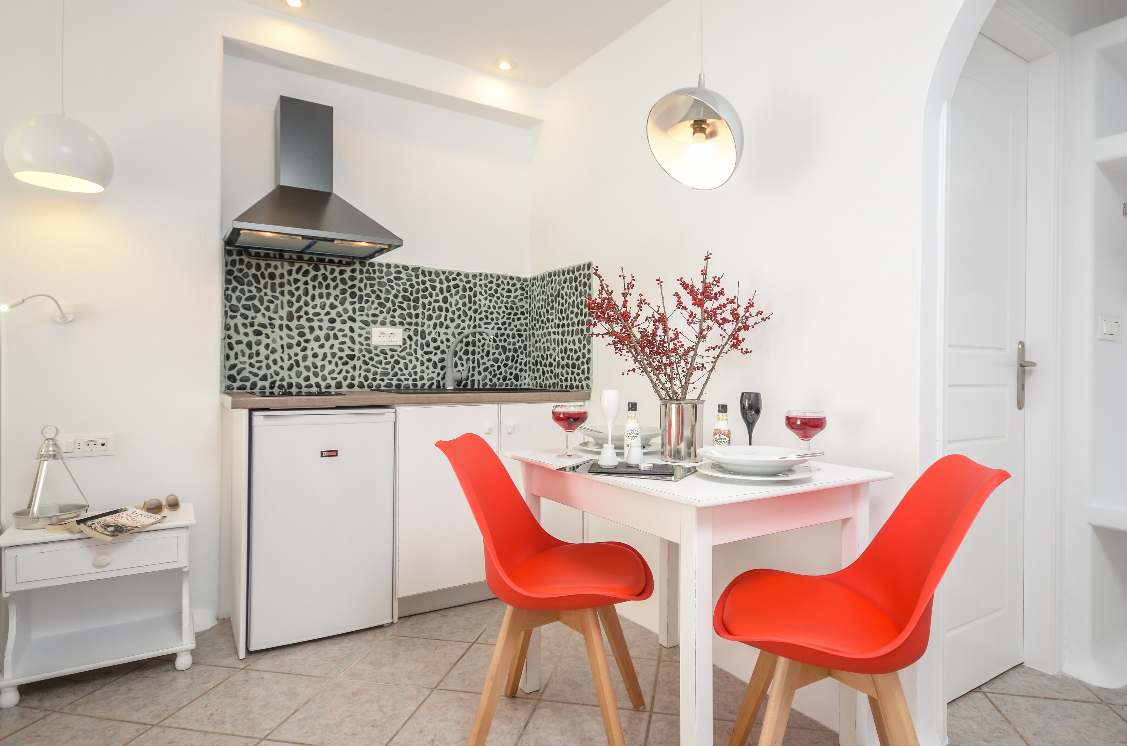 A modern kitchen with white cabinetry, a built-in stove, and a red chair at the table.