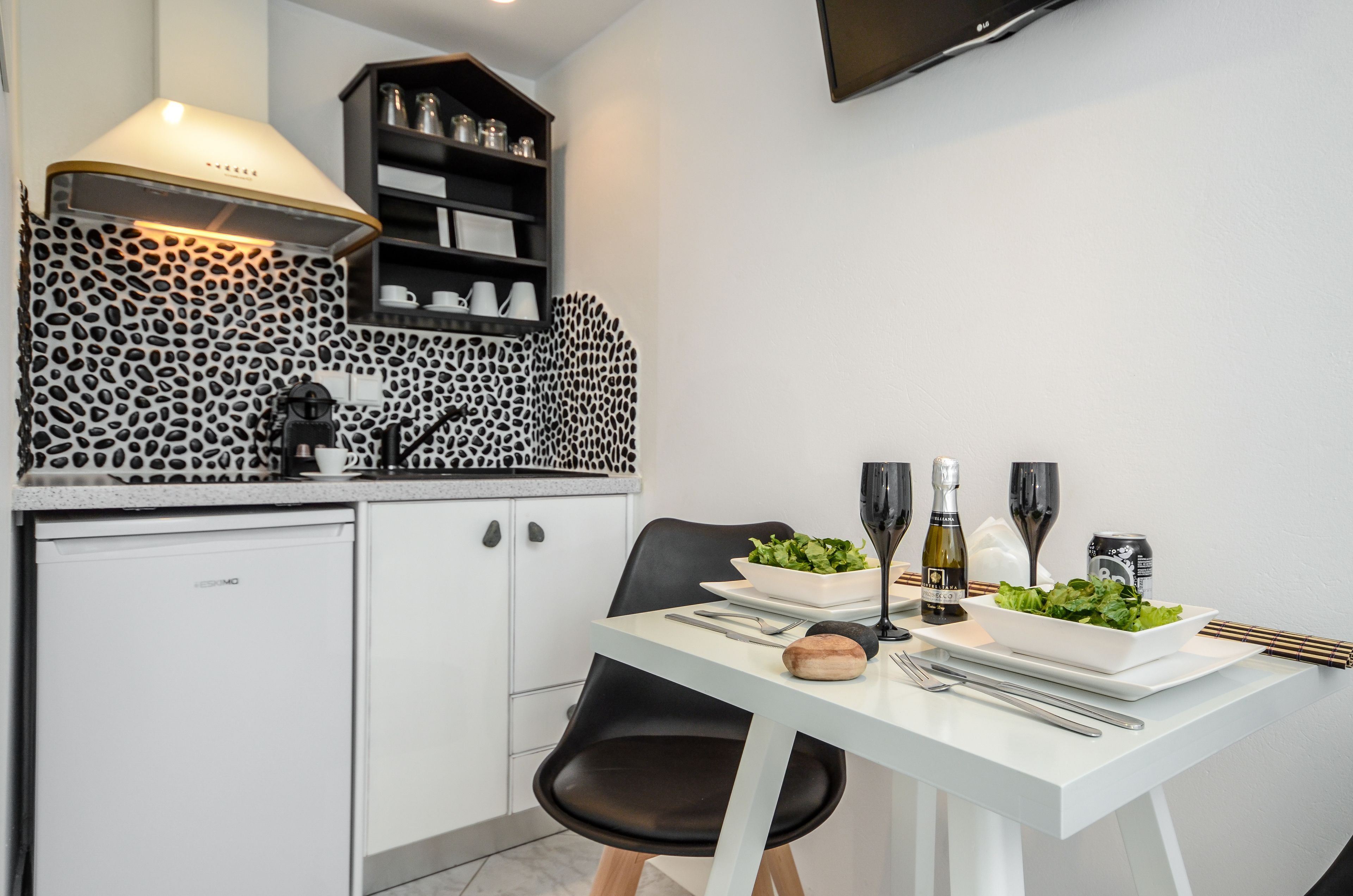A modern kitchen with a white countertop, black and white patterned backsplash, and a dining area with a white table set for two.