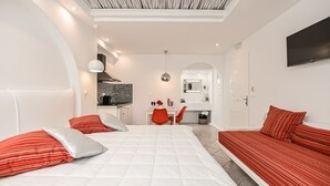 A modern bedroom with a large bed, a sofa, and a desk area. - Naxos Evilion (Naxos)